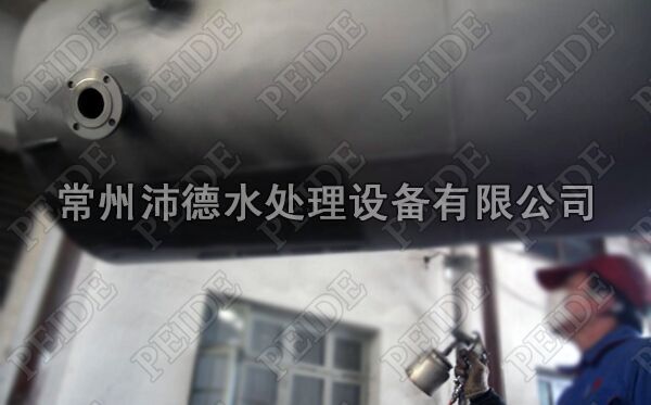 图为油漆工正在为活性砂过滤器喷清漆